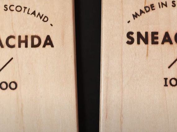 A close up of two wooden skis with made in scotland etched into the surface